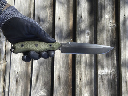 Hand holding a knife with a green handle against a wooden background