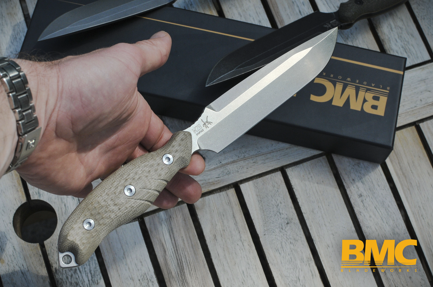 Hand holding an M28 knife with BMC branding showing great balance